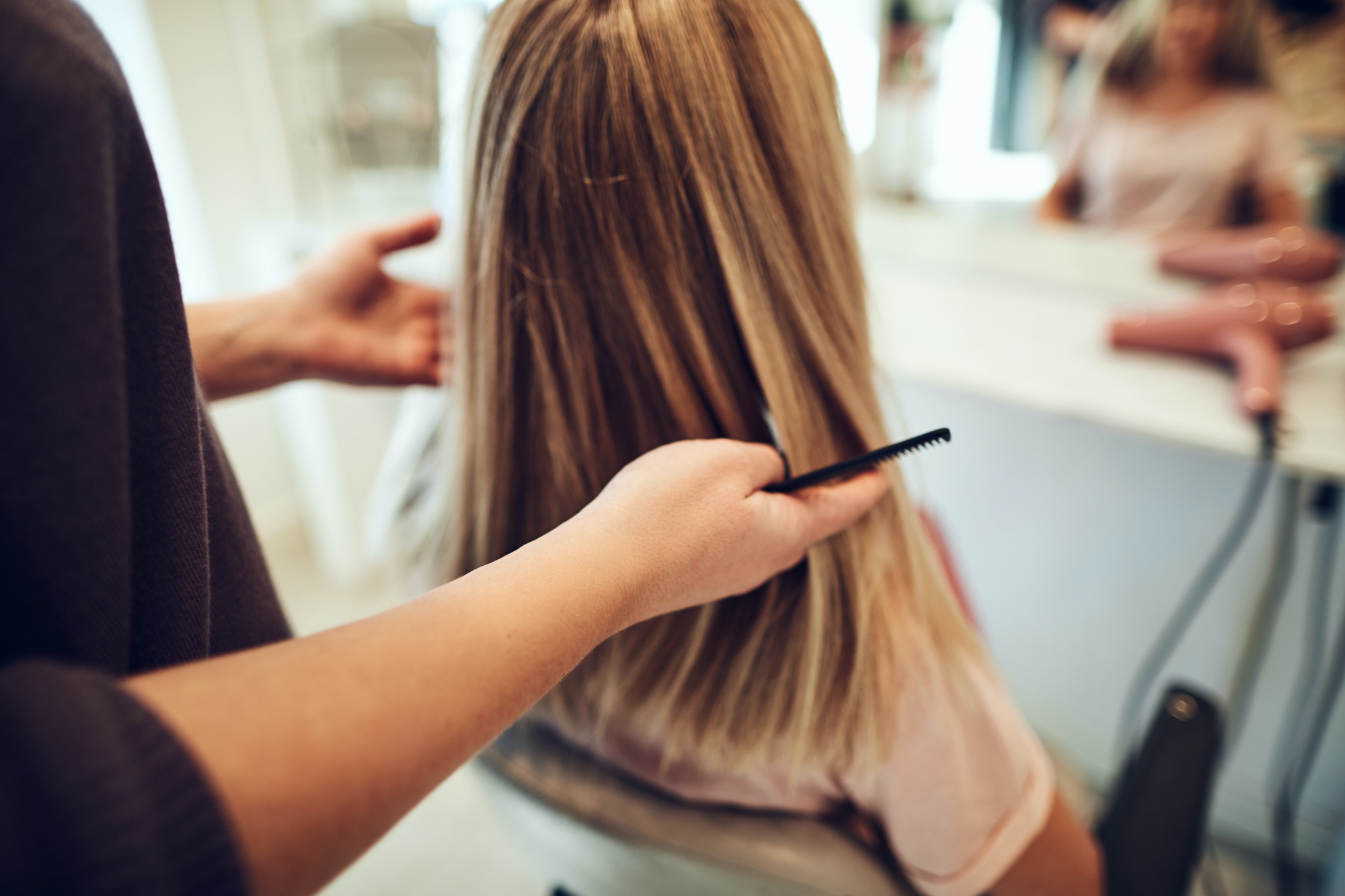 Salon hairstylist at Key Largo Tan & Spa skillfully cutting a client's hair, comb in hand, in a professional setting.